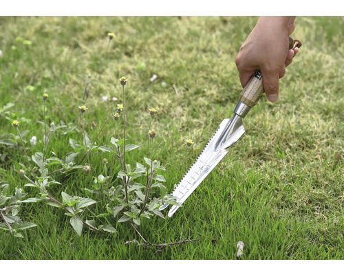 Närbild av en hand som håller en ogrässticka i gräset