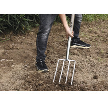 Person använder en grep i trädgården.