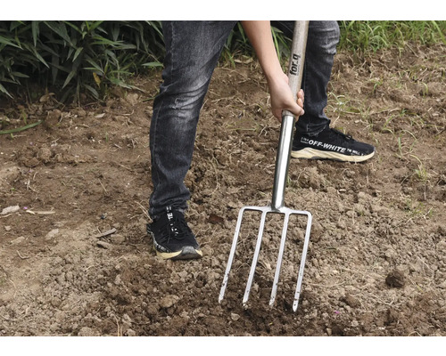 Person använder en grep i trädgården.