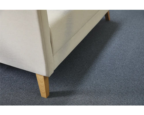 Detalj av en möbel klädd i tyg med träben på en matta.