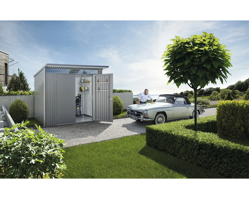 Scen med ett metallträdgårdsskjul med hyllor och en högtryckstvätt inuti. En man rengör en bil framför trädgårdsskjulet.