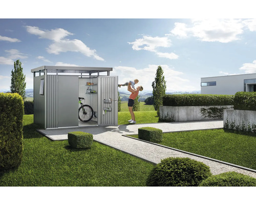 Trädgårdsscen med redskapsbod, cykel, hyllor och en kvinna som lyfter ett barn