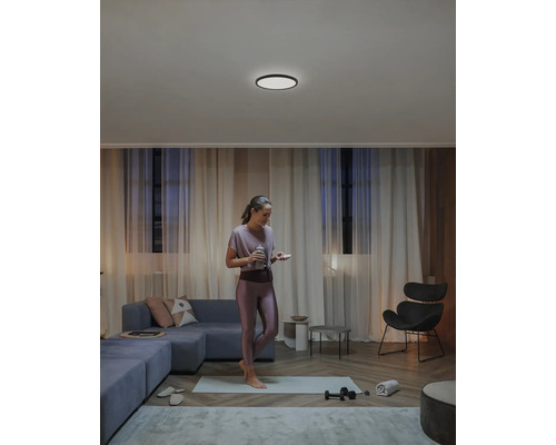 Vardagsrum med taklampa, soffa och tränande kvinna