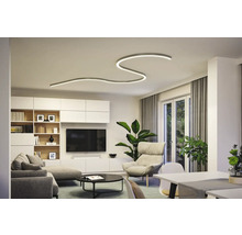 Vardagsrum med modern taklampa, soffa, fåtölj och TV-vägg.