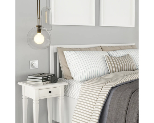 Sovrum med säng, sängbord, lampa och väggdekoration