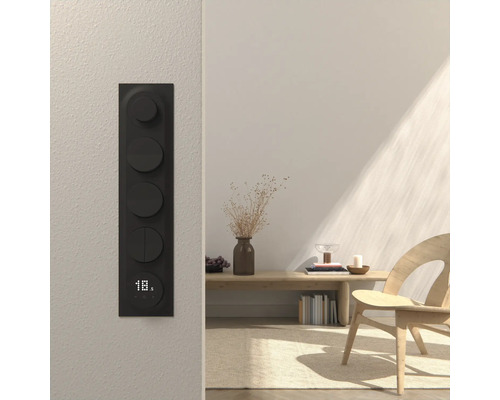 Rumsscen med en svart väggströmbrytare med vridknappar och en display som visar temperaturen