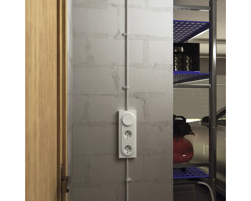 Utanpåliggande uttag med ljusströmbrytare på en vägg bredvid en dörr och en hylla.