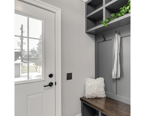 Entré med vit dörr, garderob med hyllor, bänk och dekoration