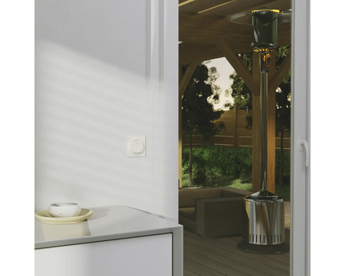 Scen med uteplatsvärmare på en träterrass, sedd från en interiör med skåp och strömbrytare