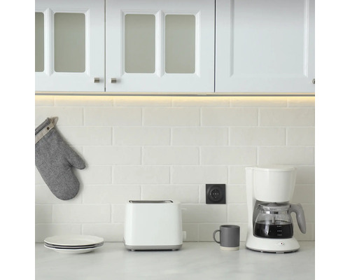 Köksscen med skåp, apparater och porslin på en arbetsyta.