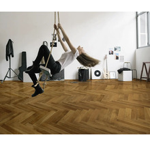 En kvinna svingar i ett rep i ett rum med ett fiskbensparkettgolv.