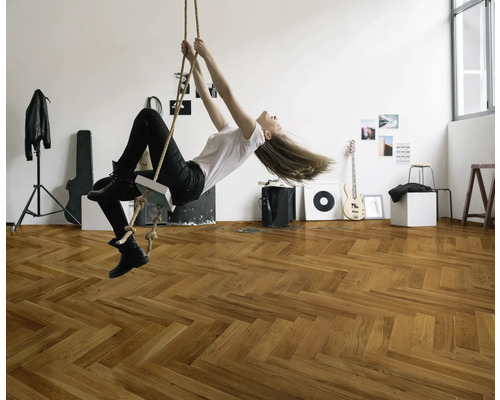 En kvinna svingar i ett rep i ett rum med ett fiskbensparkettgolv.