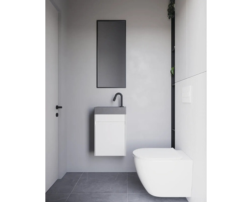 Modernt badrum med hängande tvättställ, spegel och vägghängd toalett.