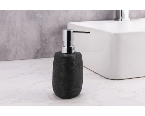 Svart keramisk tvålpump med metallpump bredvid handfat
