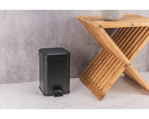 Svart metallpedalhink bredvid en träpall.