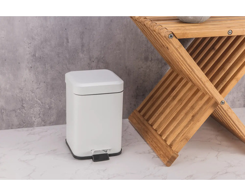 Vit metallisk pedalhink bredvid en träpall