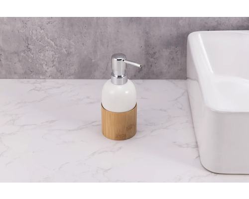Tvålpump i keramik med bambubas och krompump bredvid handfat