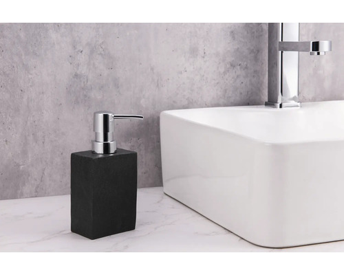 Tvåldispenser i sten bredvid ett tvättställ med kran