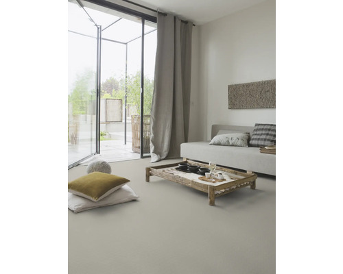 Vardagsrum med soffa, träbord, kuddar och gardiner för en ljus och vänlig atmosfär.