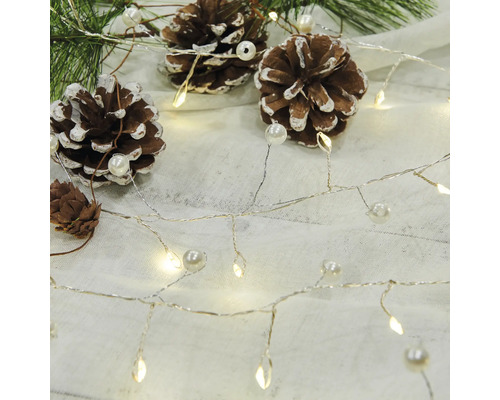 Dekorativ ljusslinga med kottar och pärlor på ljus bakgrund