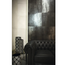 Interiör med väggplattor i metalloptik, svart lädersoffa och dekorativa vaser