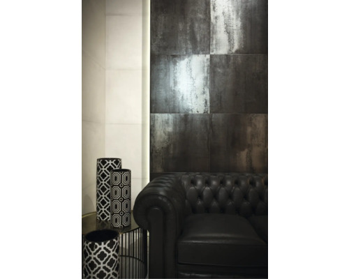 Interiör med väggplattor i metalloptik, svart lädersoffa och dekorativa vaser