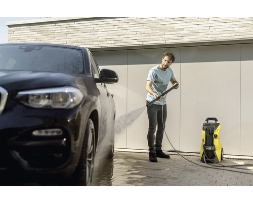 Man rengör bil med en högtryckstvätt.