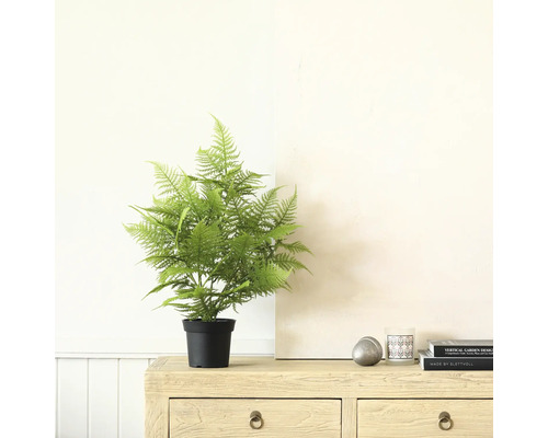 Konstgjord ormbunke i kruka på en byrå