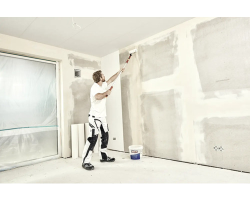 Man målar vägg med färgroller i ett rum, renoveringsprojekt