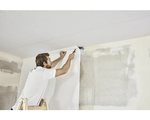 Man på stege fäster tapet på väggen