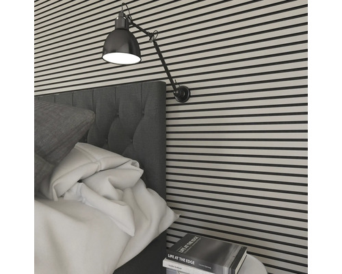 Närbild av ett sovrum med väggpaneler, en säng, en lampa och ett sängbord