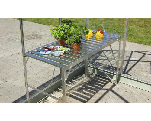 Växthusbord av metall med växter och grönsaker