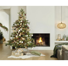 Julgran dekorerad med kulor och presenter i vardagsrummet med öppen spis.