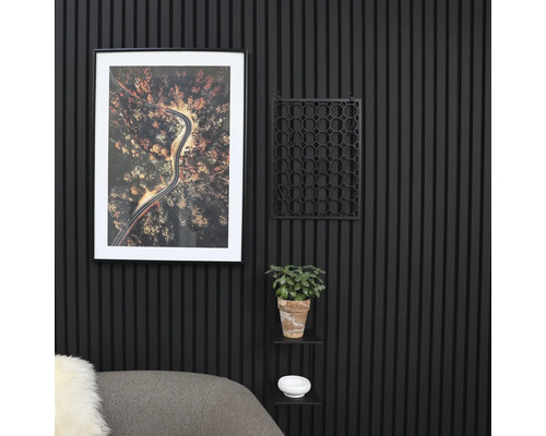 Dekorativ väggdekoration med räfflade paneler, en inramad bild, ett geometriskt rutnät, en krukväxt och en liten hylla