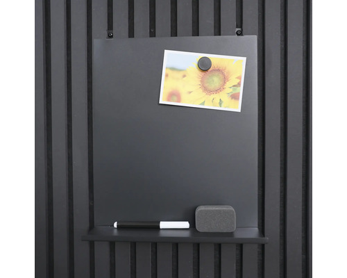 Magnetisk tavla med penna, svamp och foto monterad på en vägg.