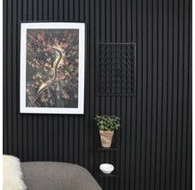 Dekorativ väggdesign med räfflade paneler, en inramad bild, en blomkruka och en liten hylla.