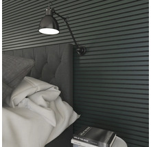 Närbild av ett sovrum med säng, sängbord, bok och vägglampa