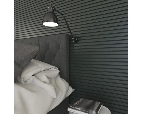 Närbild av ett sovrum med säng, sängbord, bok och vägglampa