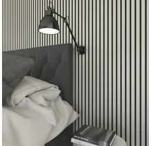 Sovrumsscen med säng, sängbord och vägglampa mot en vägg med ränder