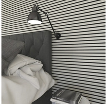 Sovrum med säng, lampa och väggbeklädnad i horisontella ränder