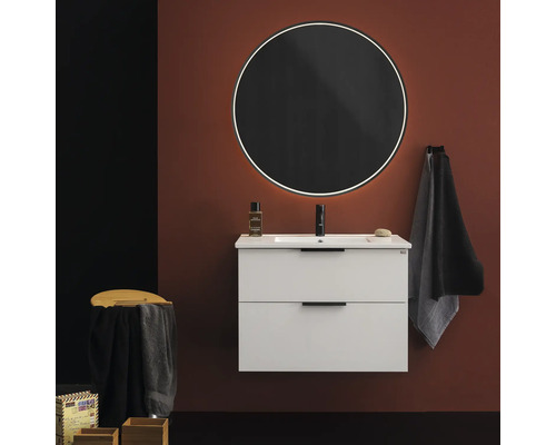 Modernt badrum med tvättställsskåp, rund spegel och handduk