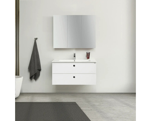 Badrum med vitt tvättställsskåp, spegelskåp och handduk