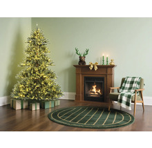 Julrum med upplyst julgran, öppen spis och fåtölj