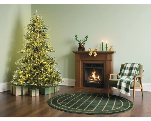 Julrum med upplyst julgran, öppen spis och fåtölj