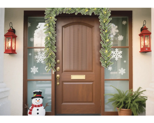 Dekorerad ytterdörr med girlang, lyktor, snöflingeklistermärken och snögubbe