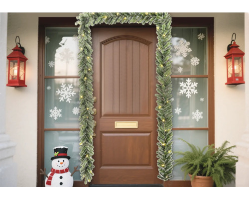 Dekorerad entré med grangirlang, lyktor och snögubbe