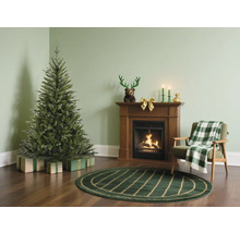 Julscen med julgran, öppen spis och fåtölj i ett vardagsrum