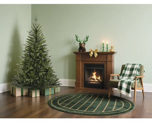 Julscen med julgran, öppen spis och fåtölj i ett vardagsrum