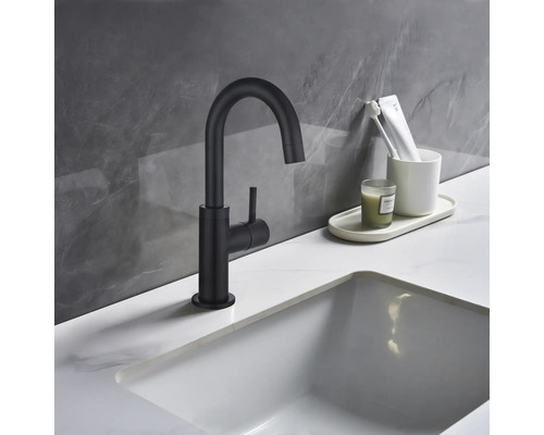 Svart tvättställsblandare bredvid ett handfat i ett badrum.