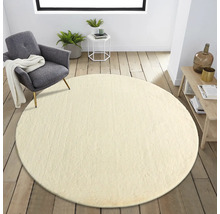 Vardagsrum med rund matta, fåtölj och sidobord på trägolv